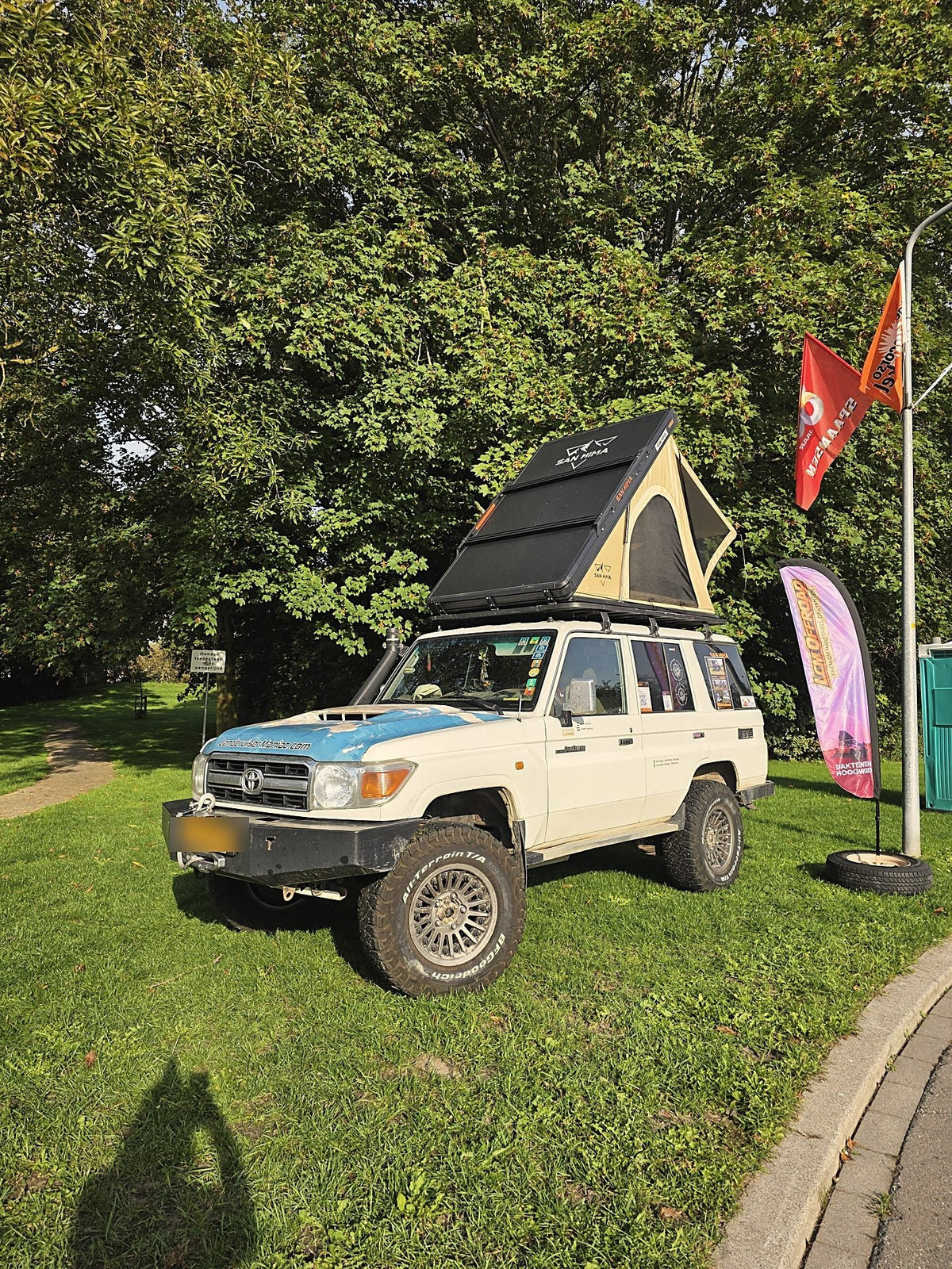 Land Cruiser met opengeklapte khaki LCM hardshell daktent en LCM Offroad beachflag