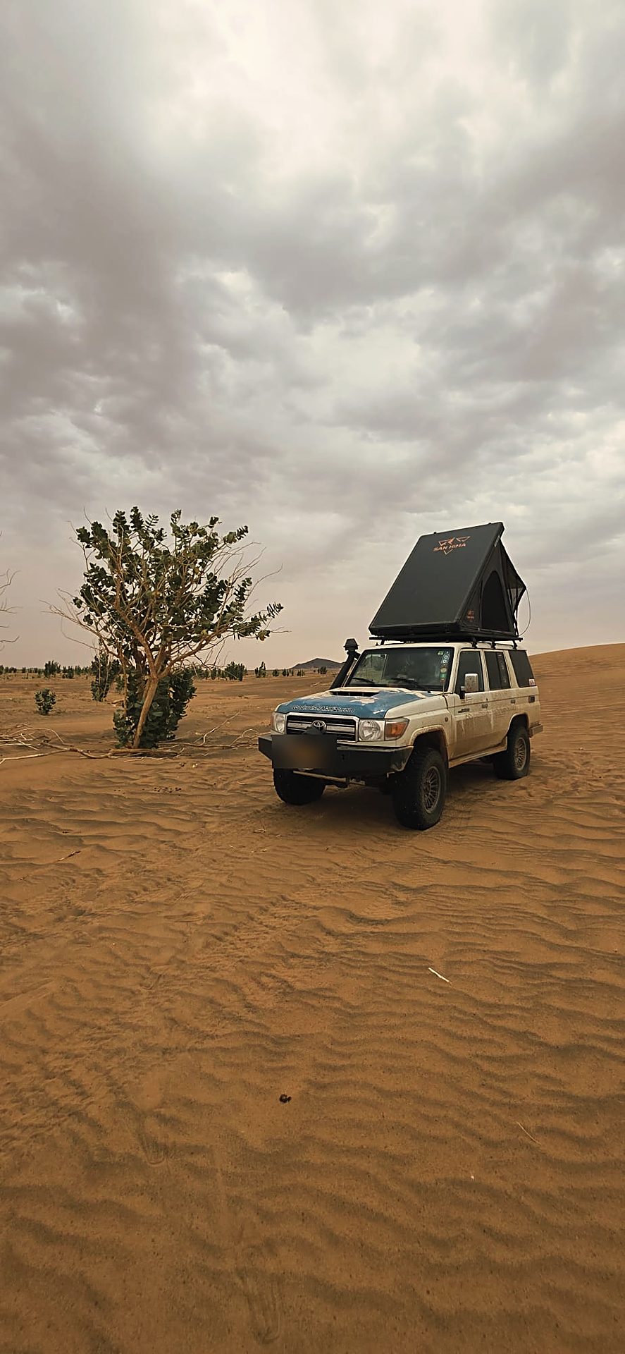 LCM hardshell daktent opengeklapt op een duin onder een bewolkte lucht