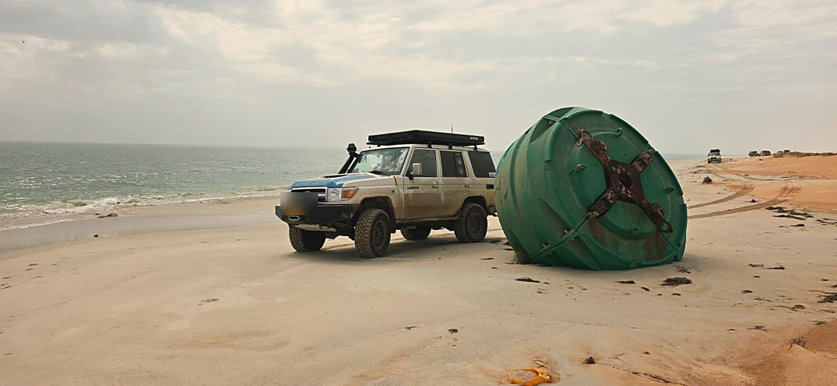 Land Cruiser on the coast beside a washed-up buoy