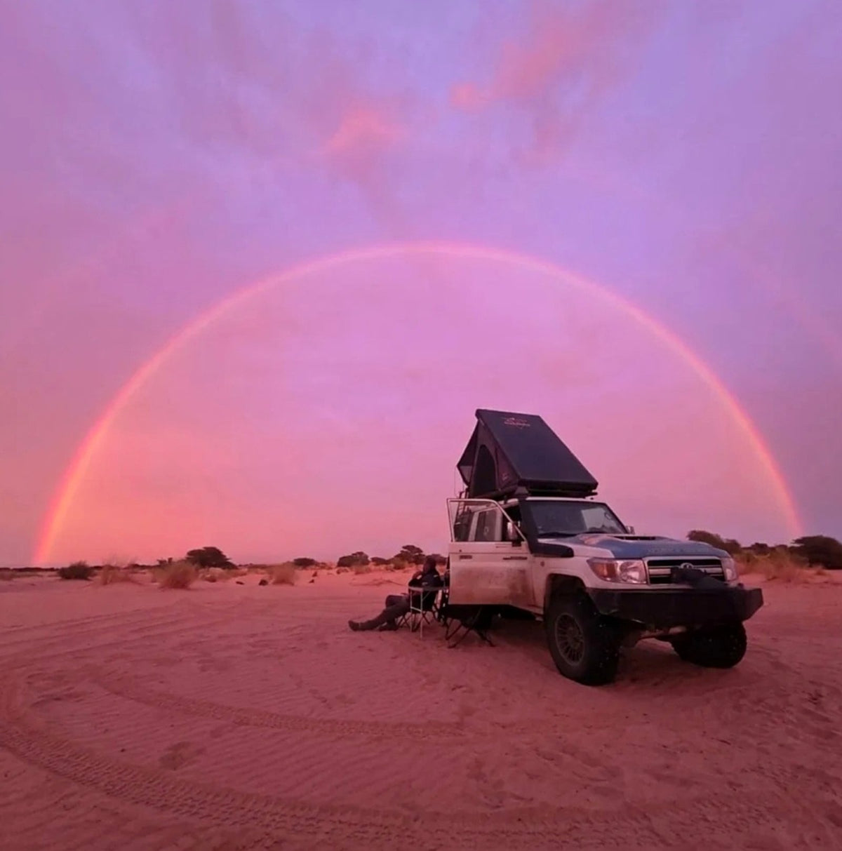 Land Cruiser with the LCM hardshell rooftop tent open under a full rainbow in the Sahara at dusk