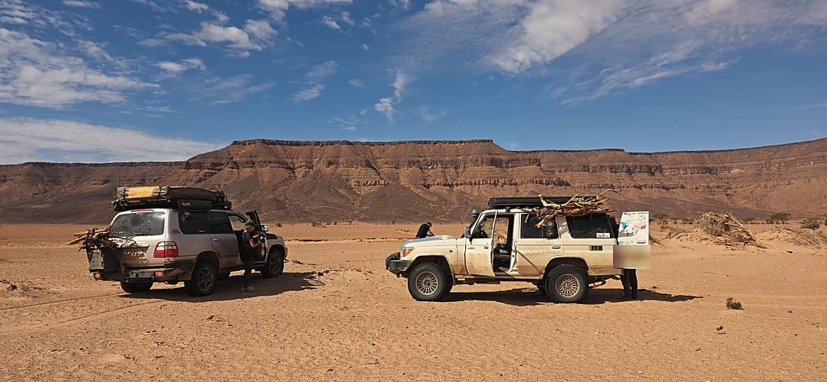 Two Land Cruisers with firewood by a table mountain in the Sahara