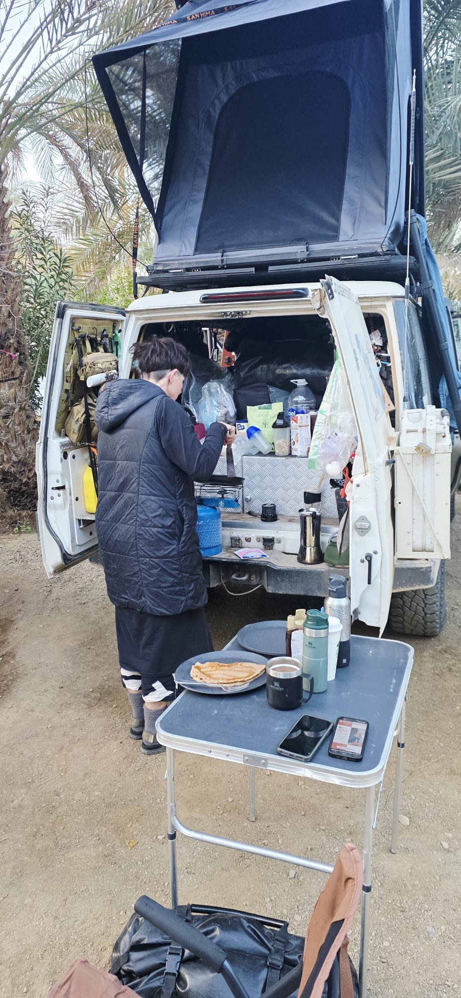 Cooking beside the open LCM rooftop tent in an oasis